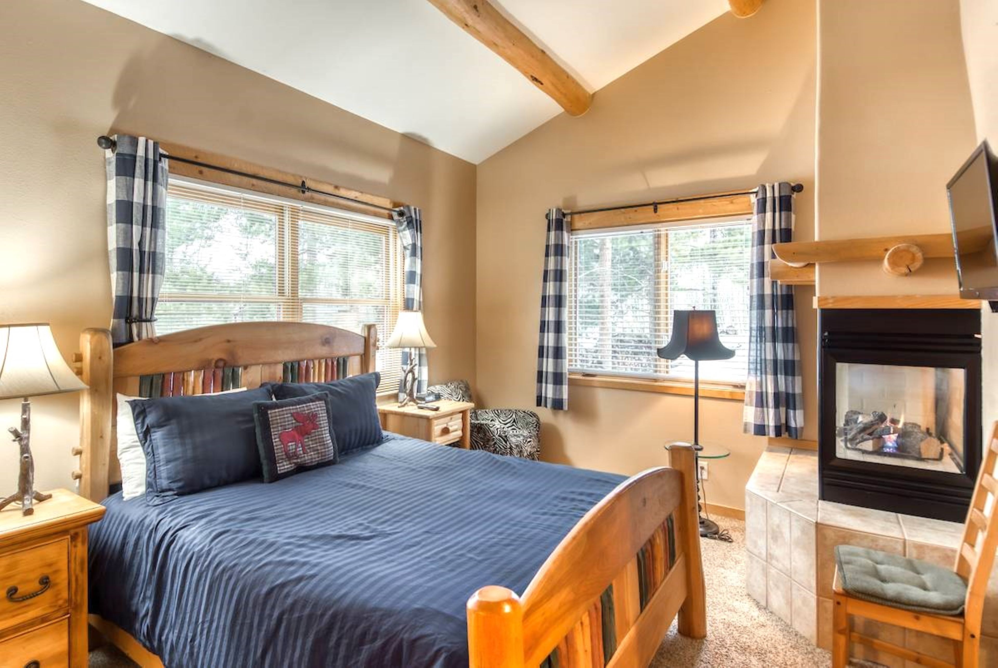 Une chambre confortable avec un lit, des tables de chevet, une lampe, une cheminée et des fenêtres avec des rideaux.