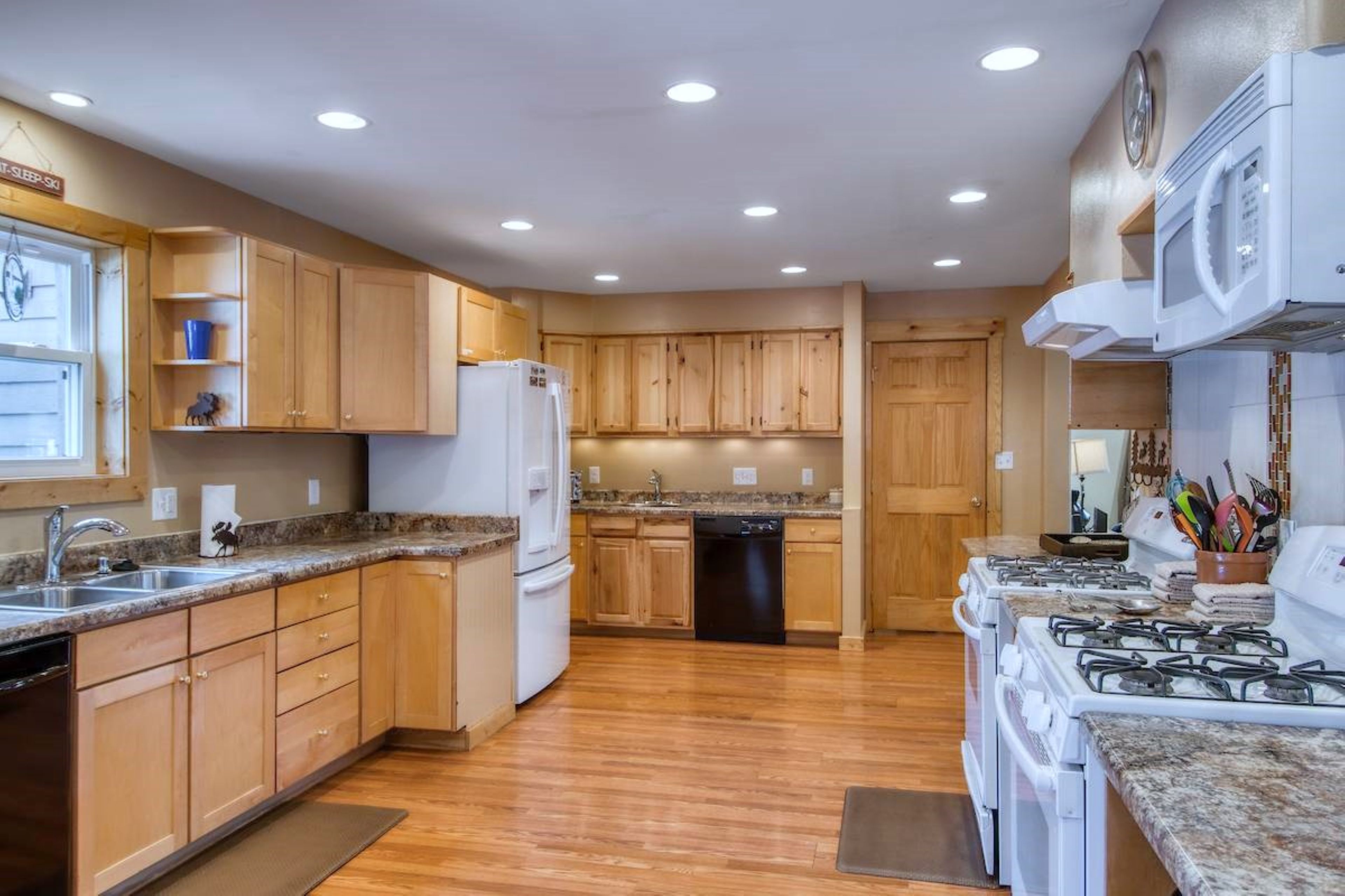A kitchen with wooden cabinets, a refrigerator, a dishwasher, and a stove.