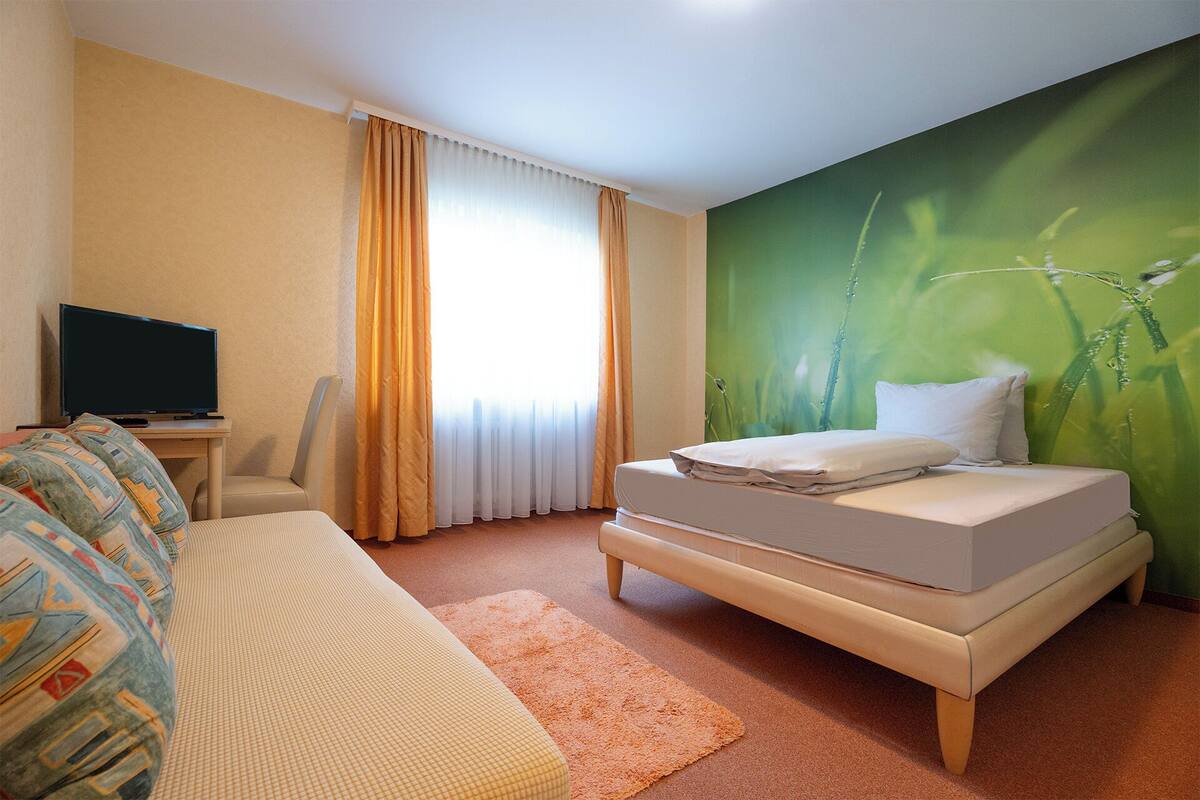 Habitació d'hotel amb un llit, una televisió, un escriptori i un sofà.