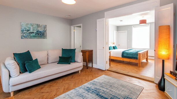 Un salon moderne avec un canapé, un tapis et un tableau accroché au mur.