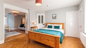 Une chambre à coucher avec un lit en bois, une porte blanche et un couloir menant à une autre pièce.