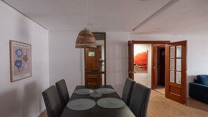 A dining area with a dark wooden table, four chairs, and a hanging light fixture.