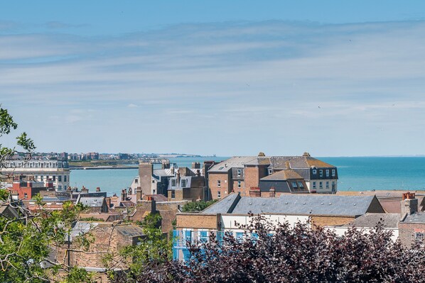A coastal town with buildings close to the water, a clear sky, and a view of the sea.
