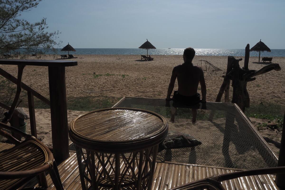 A beach view with a wooden deck, chairs, and umbrellas.