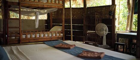 A room with bunk beds, a fan, and a table with chairs.