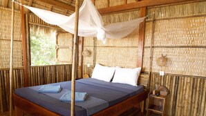 Una habitación con cama, mesita de noche, una cesta colgante y una ventana.