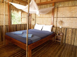 Um quarto com cama, mesa de cabeceira, cesta suspensa e janela.