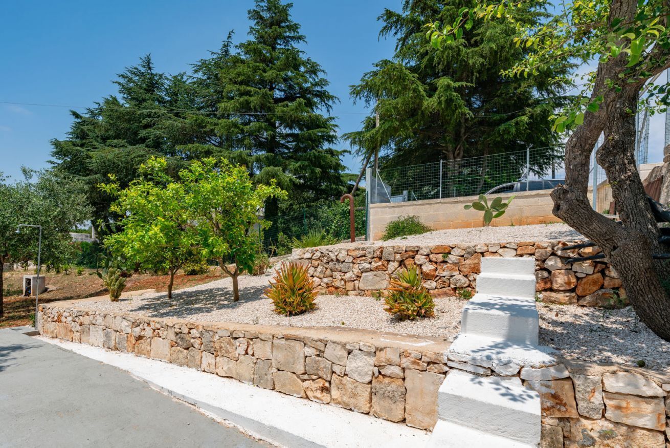 A stone pathway leading to a building, surrounded by trees and a clear sky.