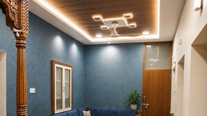 A modern living room with a blue sofa, a wooden coffee table, and a wooden cabinet. - Hotel Robin Jaisalmer (Jaisalmer)