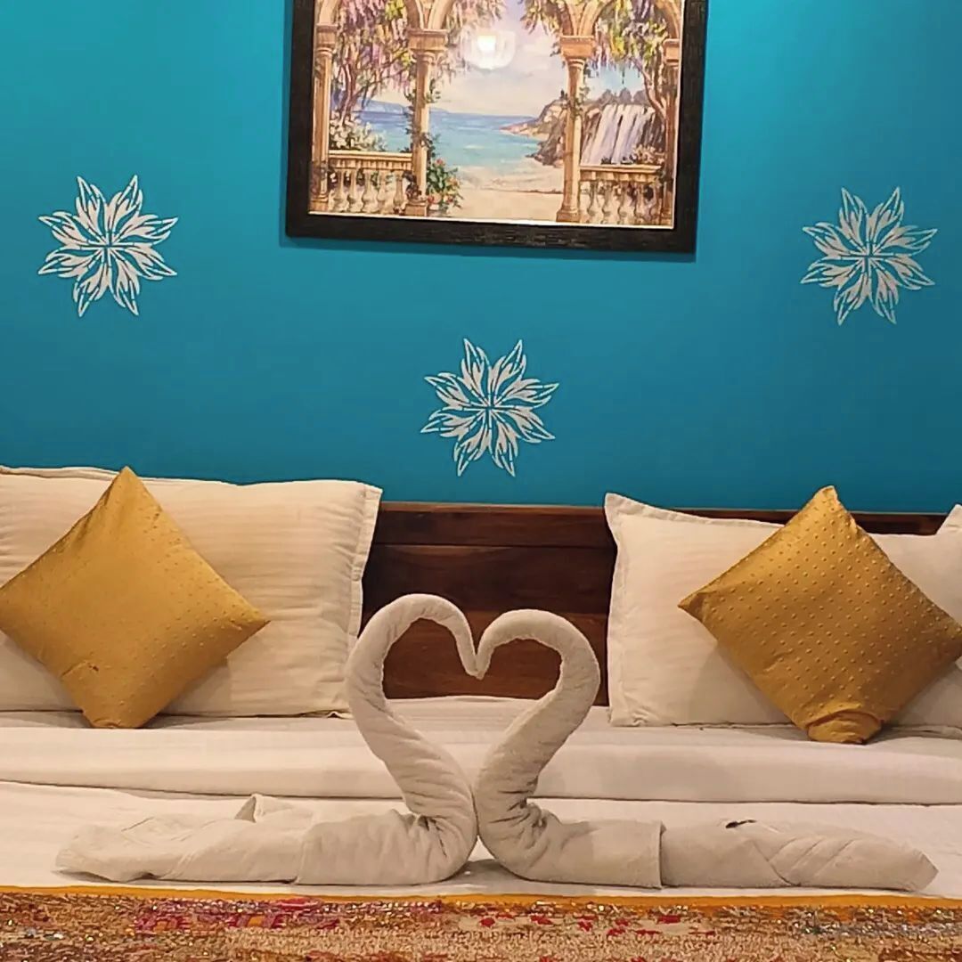 Una cama con una decoración de toallas en forma de corazón, una pared azul con un cuadro enmarcado y adornos de copo de nieve en la pared.