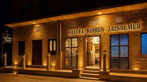 A hotel exterior with a stone facade, large windows, and a sign reading 'HOTEL ROBIN JAISALMER.' - Hotel Robin Jaisalmer (Jaisalmer)