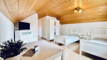 Ein Schlafzimmer mit Holzboden, einem Bett, einem Nachttisch, einem Fernseher, einem Kleiderschrank und einer Pflanze.