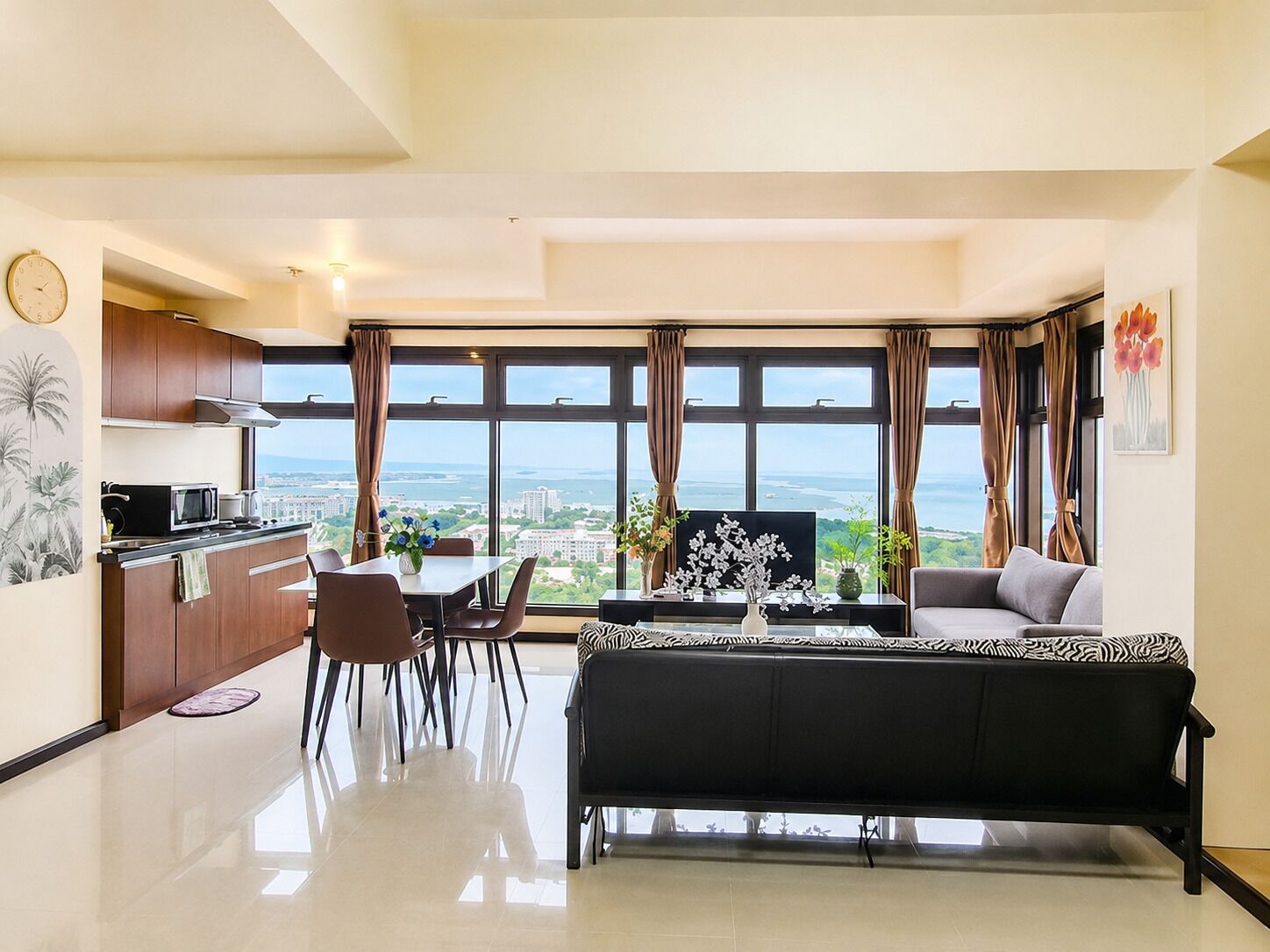 A modern living room with a sofa, dining table, chairs, and a kitchen area with a view.