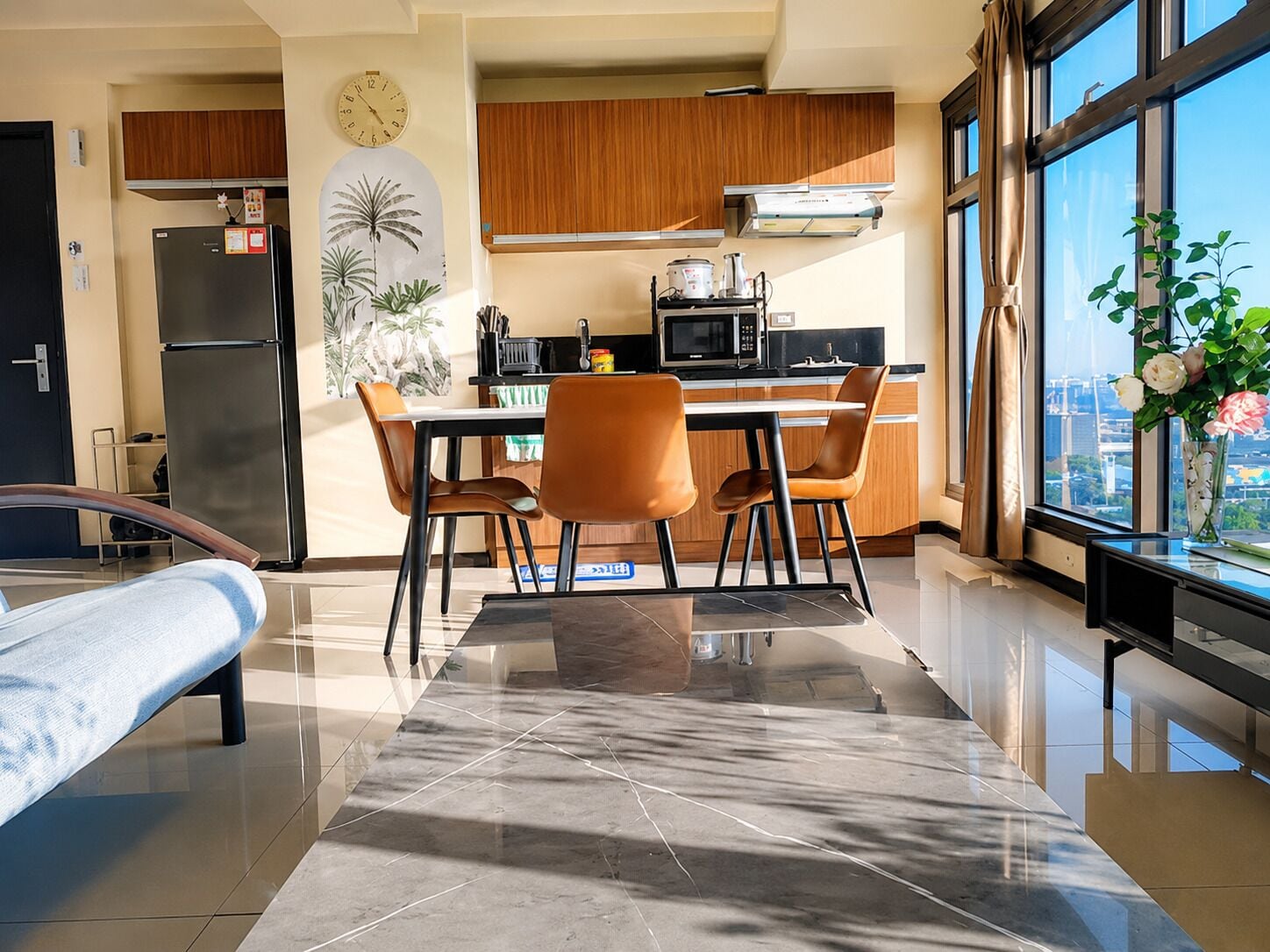 Una cocina moderna con armarios de madera, un refrigerador y una zona de comedor con mesa y sillas.