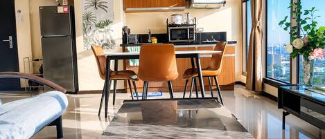 Una cocina moderna con armarios de madera, un refrigerador y una zona de comedor con mesa y sillas.