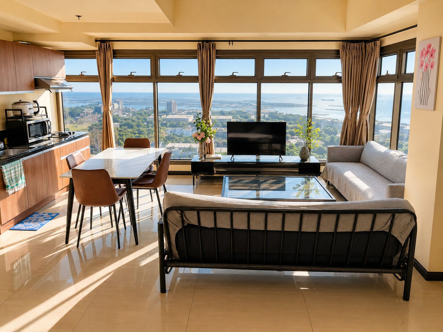 Una sala moderna con comedor, sofá, televisor y cocina con vistas.