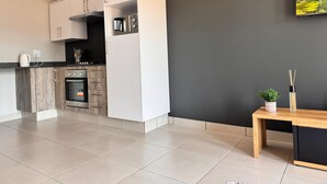 Una cocina moderna con armarios blancos, horno empotrado y cafetera.