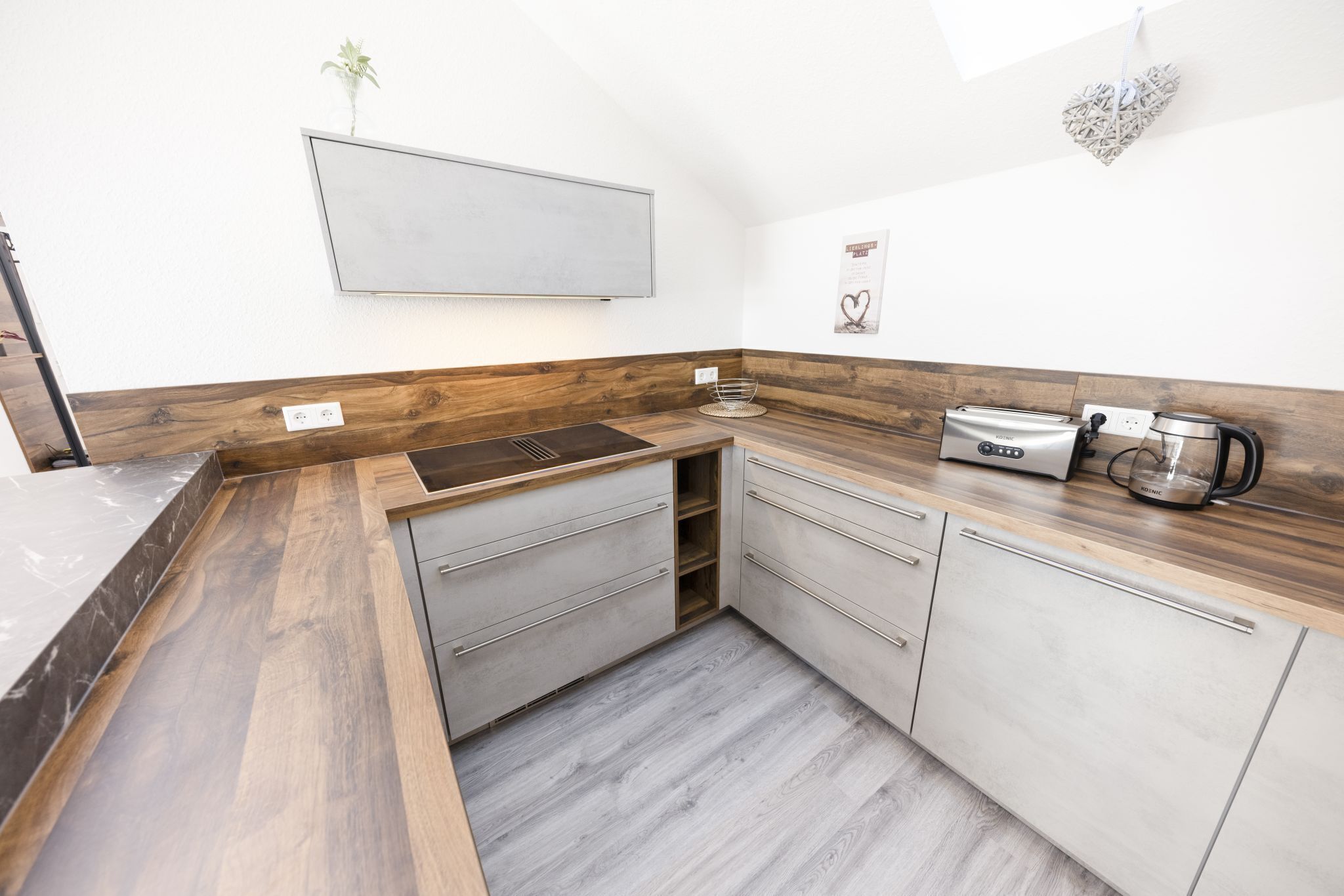 A compact kitchen with a wooden countertop, built-in cabinets, and a wall-mounted TV.