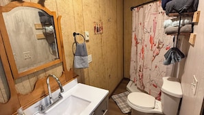 Un baño de madera pequeño y funcional con lavamanos, espejo y retrete.