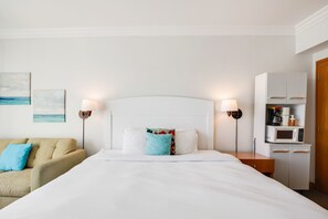 A hotel room with a bed, a sofa, a nightstand, a lamp, a microwave, and a cabinet. - Oceanfront Studio | Near Condado & Escambrón Beach (San Juan)