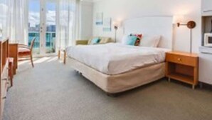 Ein Hotelzimmer mit Bett, Nachttisch, Lampe und Blick ins Freie.