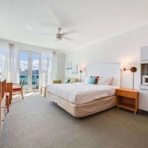 Ein Hotelzimmer mit Bett, Nachttisch, Lampe und Blick ins Freie.
