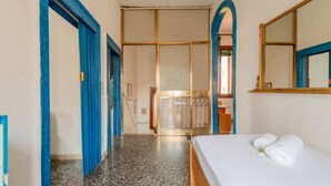 Quarto de hotel com uma cama, um espelho e um guarda-roupa.