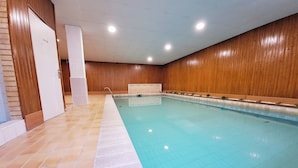 Ein Innenpool mit gefliestem Boden und Holzverkleidung.