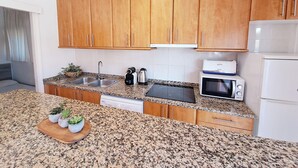 Eine Küche mit Granit Arbeitsplatten, Holzschränken, einer Mikrowelle, einem Toaster und einem Geschirrspüler.