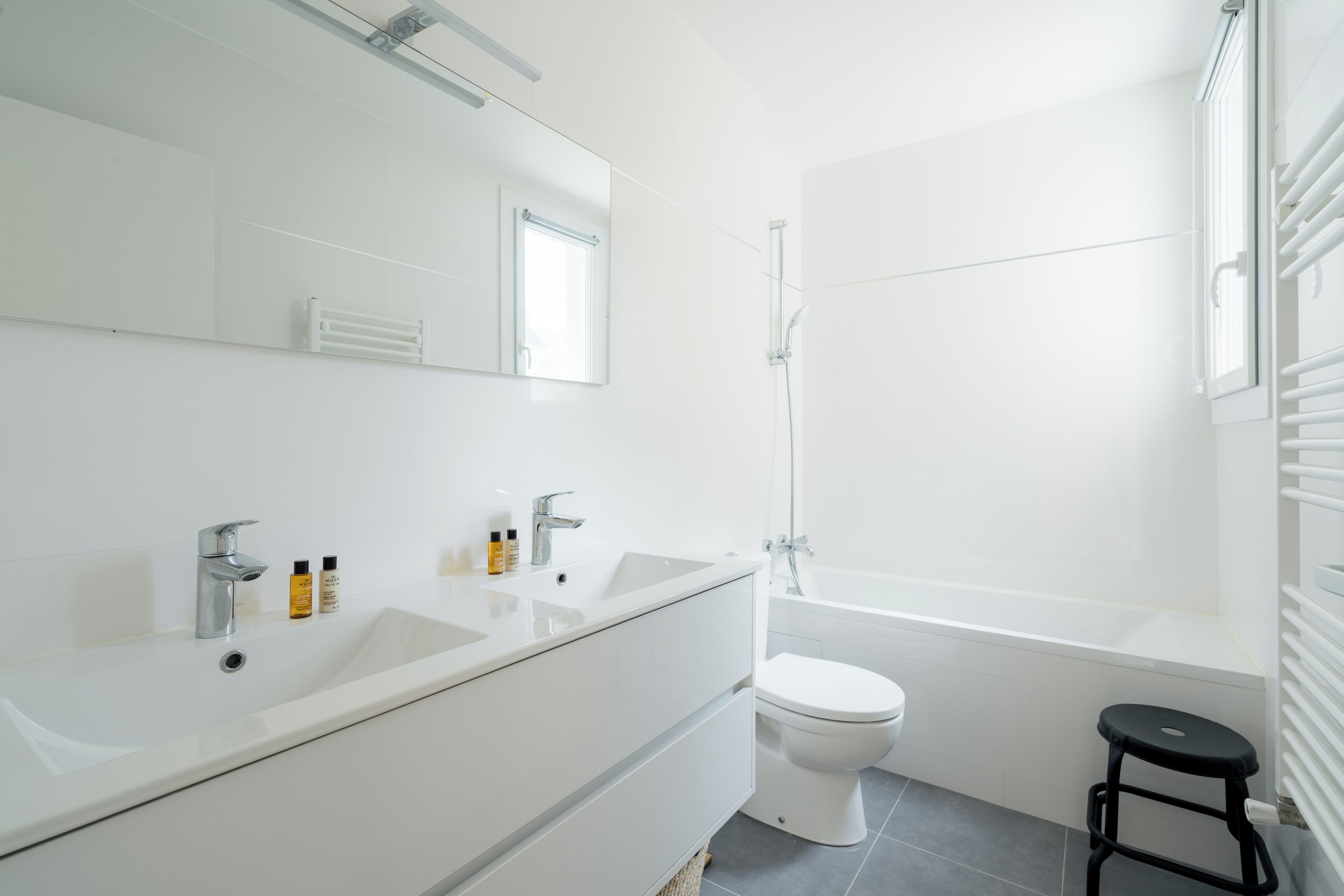 A modern bathroom with a white sink, mirror, and toilet.