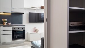 A modern kitchen with built-in appliances, a flat-screen TV, and a cozy seating area with a bench. - 7Studios - 6 Purple (Milano)