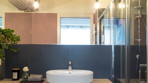 A modern bathroom with a round sink, a glass shower enclosure, and a potted plant. - 7Studios - 6 Purple (Milano)