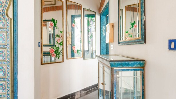 Un pasillo con piso de baldosas, pared azul de azulejos y un aparador de vidrio con encimera de mármol azul.