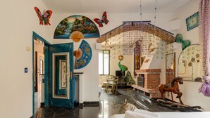 Una habitación amplia con chimenea, una estatua de pavo real y un caballito de madera.