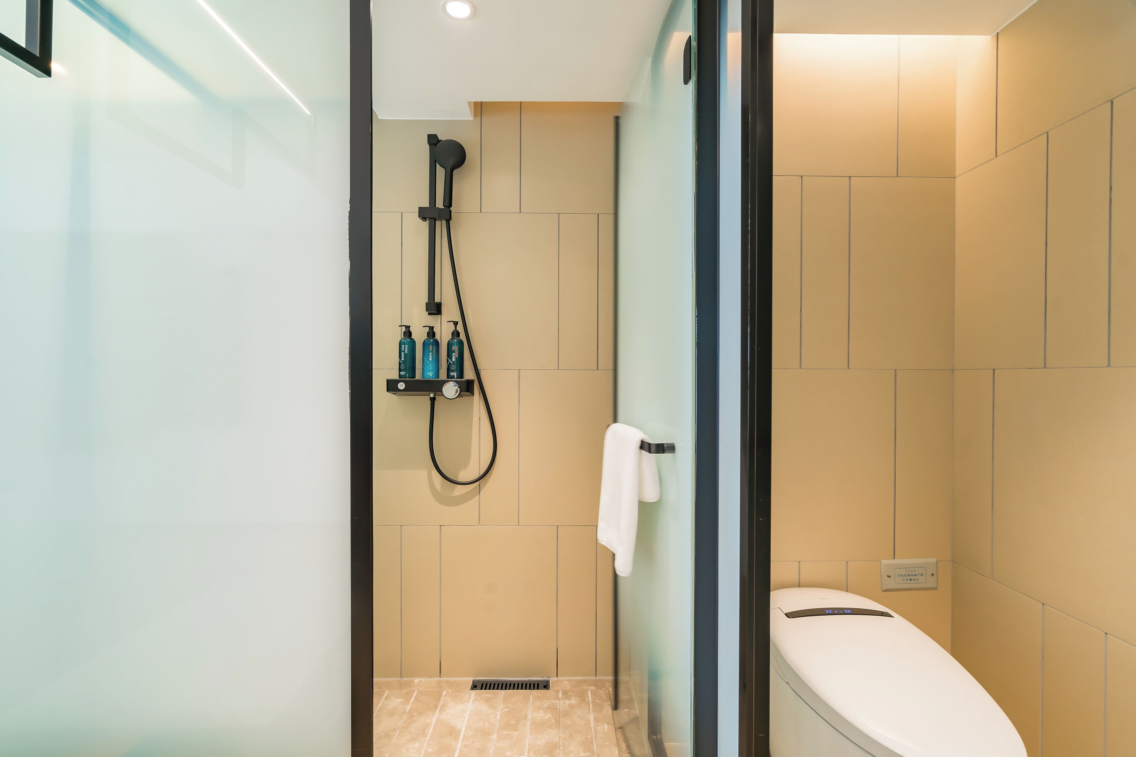 Un baño moderno con cabina de ducha de vidrio, inodoro y perchero para toallas.