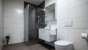 Une salle de bain moderne avec une douche à parois de verre, des toilettes blanches et un meuble-lavabo avec un miroir.