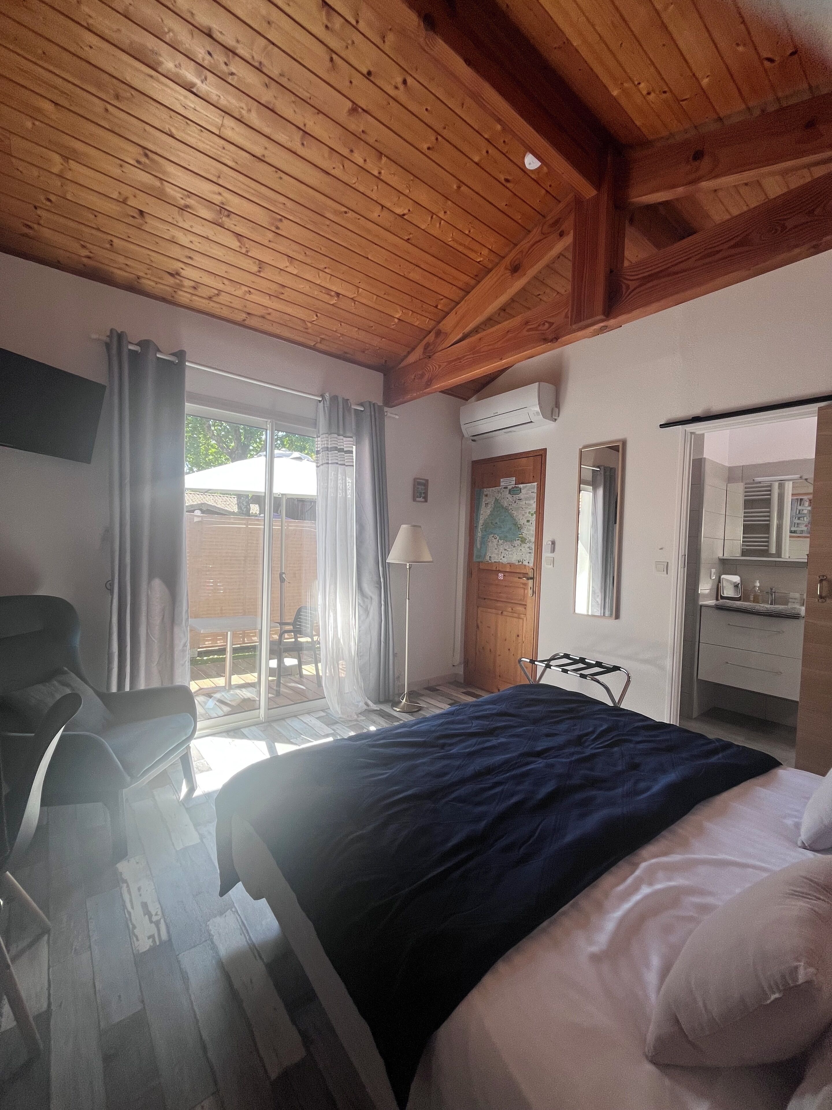 Een slaapkamer met een bed, een stoel, een lamp, een raam en een airconditioning.