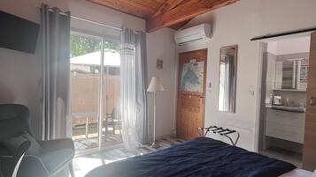 Een slaapkamer met een bed, een stoel, een lamp, een raam en een airconditioning.