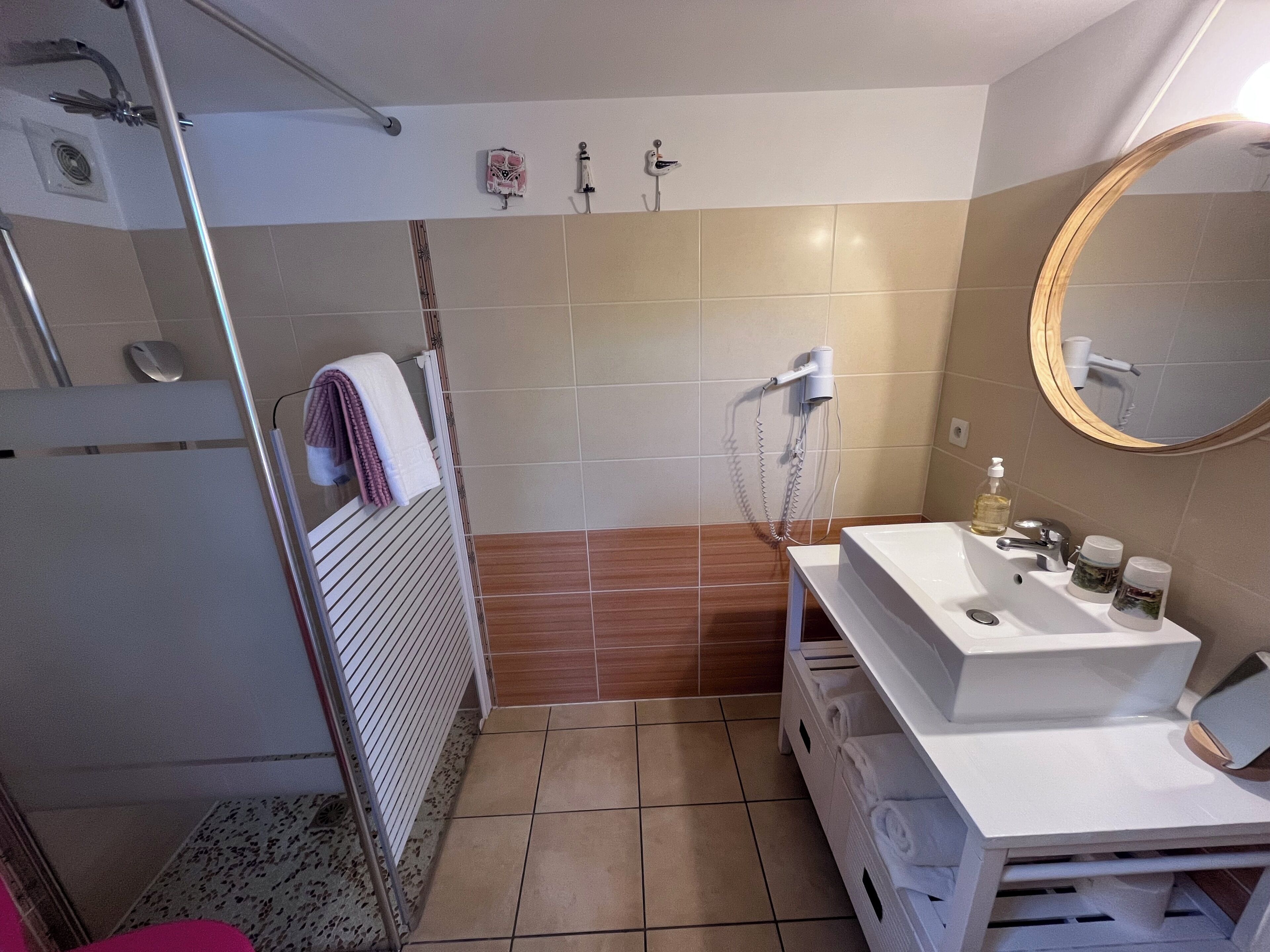 A bathroom with a shower, a sink with toiletries, and a mirror.