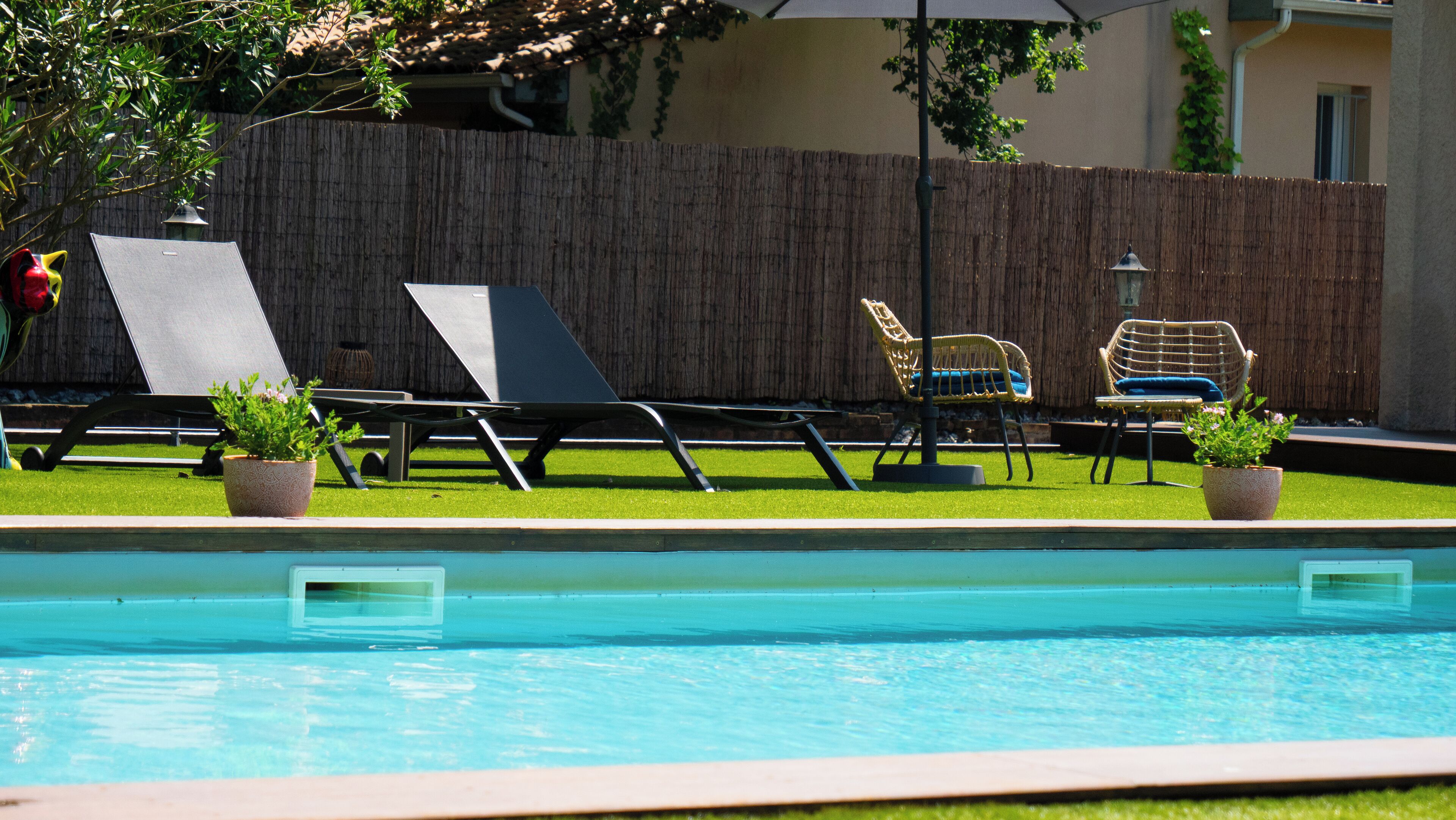 A swimming pool with lounge chairs and potted plants.