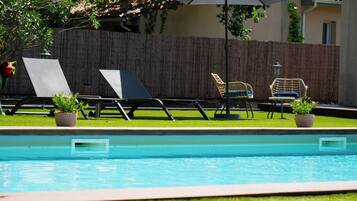 Ein Pool mit Liegestühlen und Topfpflanzen.