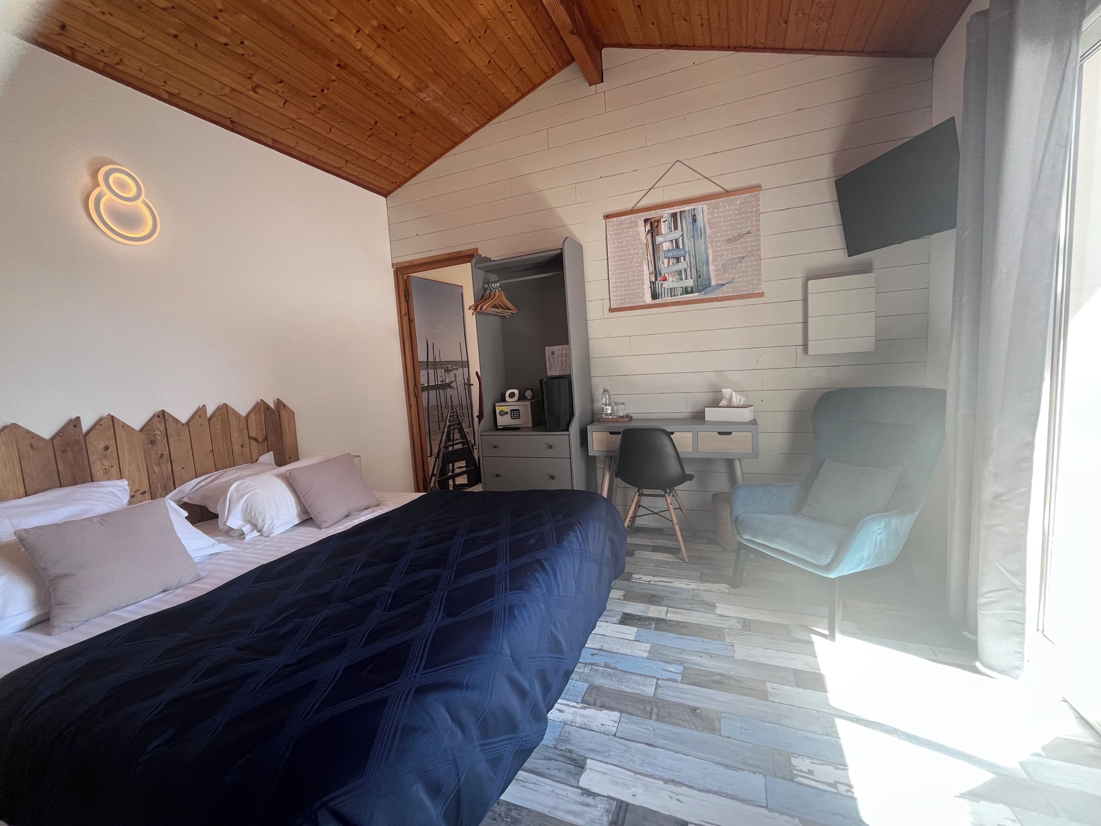 A bedroom with a bed, a desk, a chair, and a large mirror.