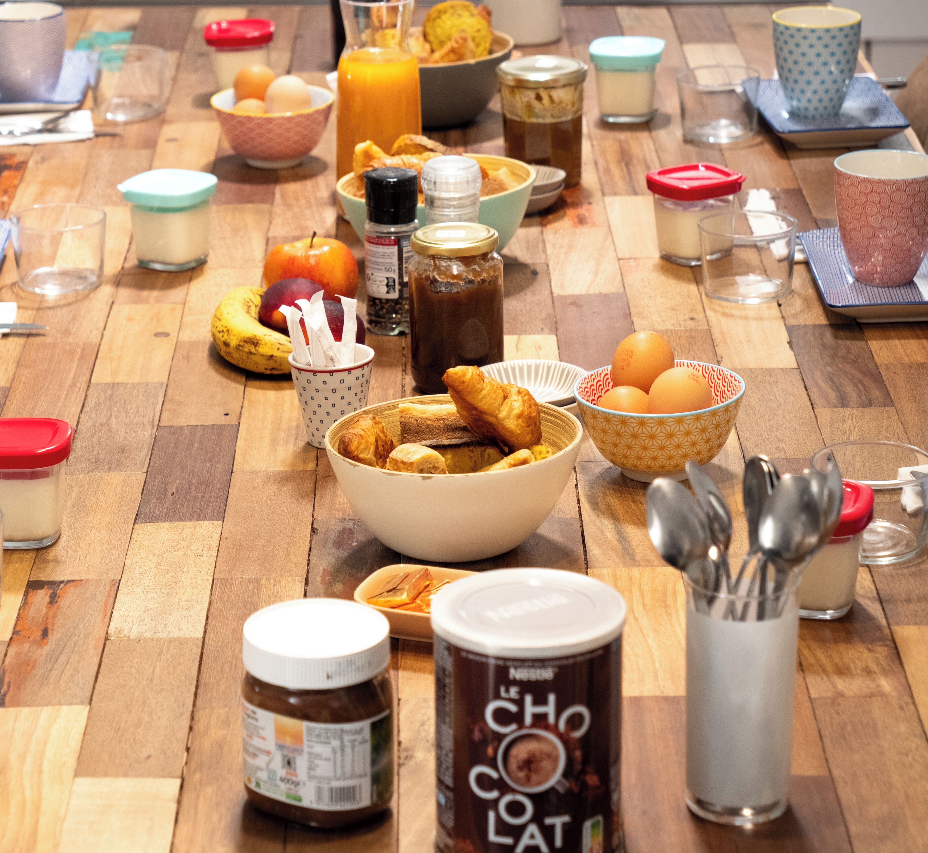 Una mesa de madera con diversos alimentos para el desayuno, como huevos, pan y salsas.