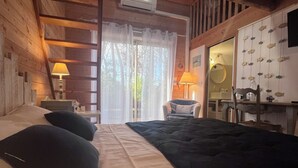 Ein gemütliches Schlafzimmer mit einem großen Bett, zwei Nachttischlampen, einer Holzbalkendecke und einem Fenster mit Vorhängen.