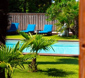 A swimming pool with blue lounge chairs and a wooden fence in the background. - VILLA HERBERT (Andernos-les-Bains)