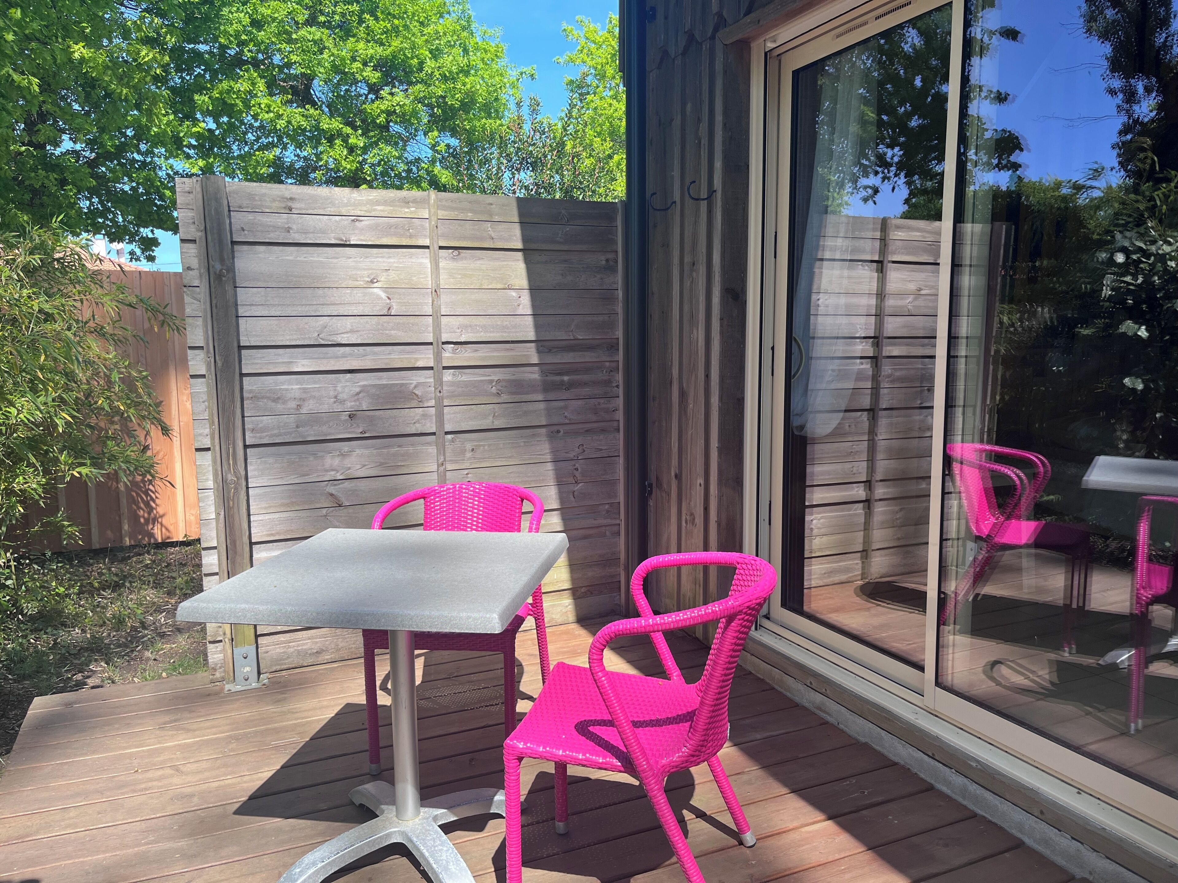 Una terraza de madera con una mesa y dos sillas.