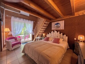 A bedroom with a bed, a chair, a table, a lamp, and a staircase. - VILLA HERBERT (Andernos-les-Bains)
