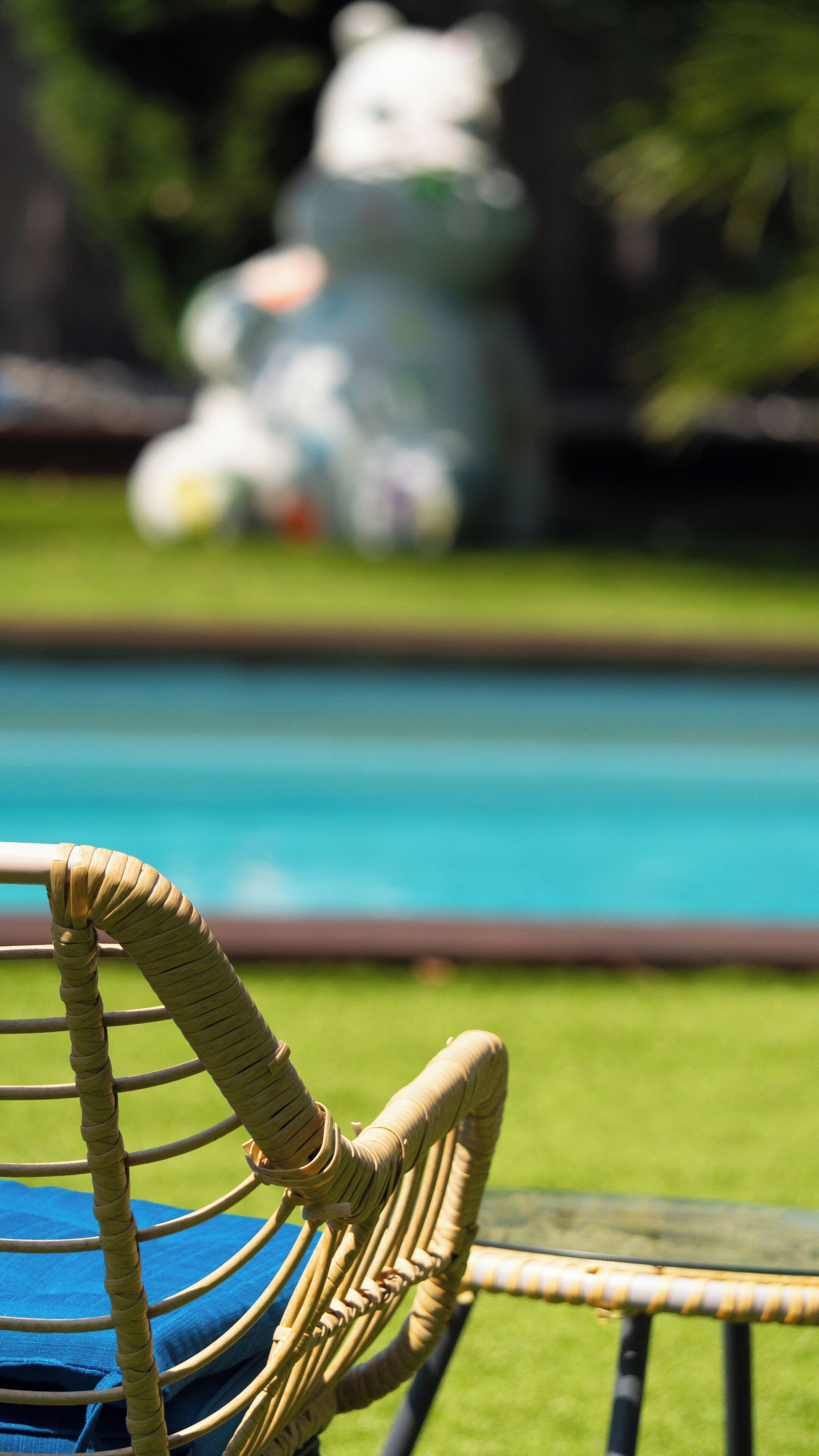 A wicker chair with a blue cushion by a pool.