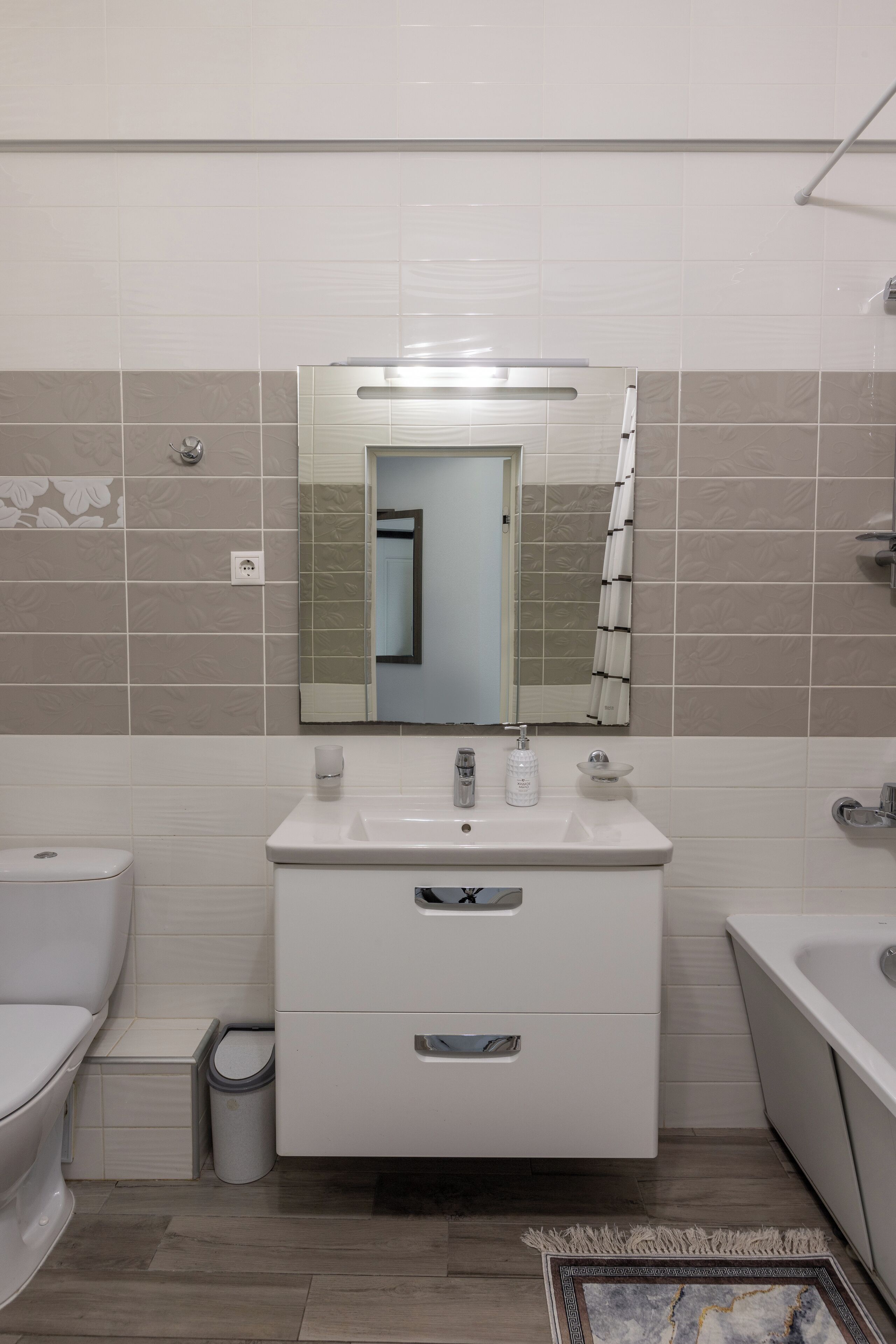 A bathroom with a toilet, sink, and mirror.