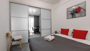 Une chambre d’hôtel moderne avec un grand lit, des oreillers rouges, une chaise en bois et un tableau représentant une rose.